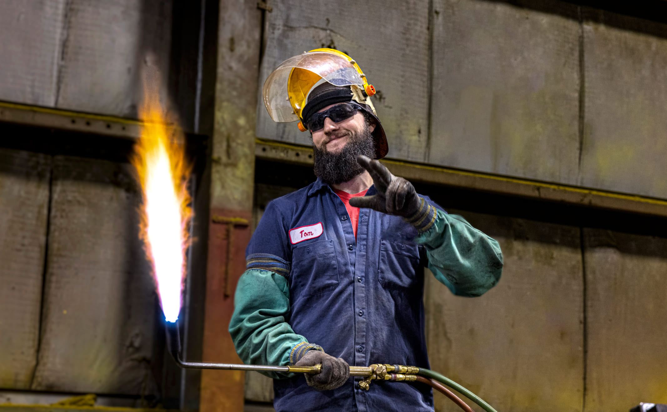 Zenar welder smiling and holding torch with large flame